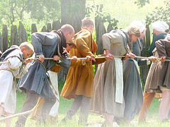 Image of many people pulling a rope to wind a trebuchet at a medieval fair